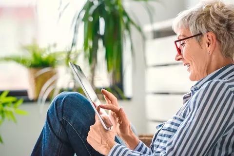 Eine ältere Dame schaut auf ihr Tablet