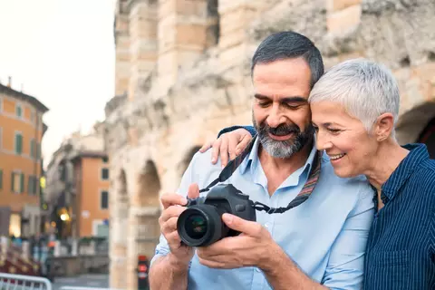 Ein Paar schaut sich im Urlaub die gerade gemachten Fotos auf dem Bilschirm des Fotoapparates an